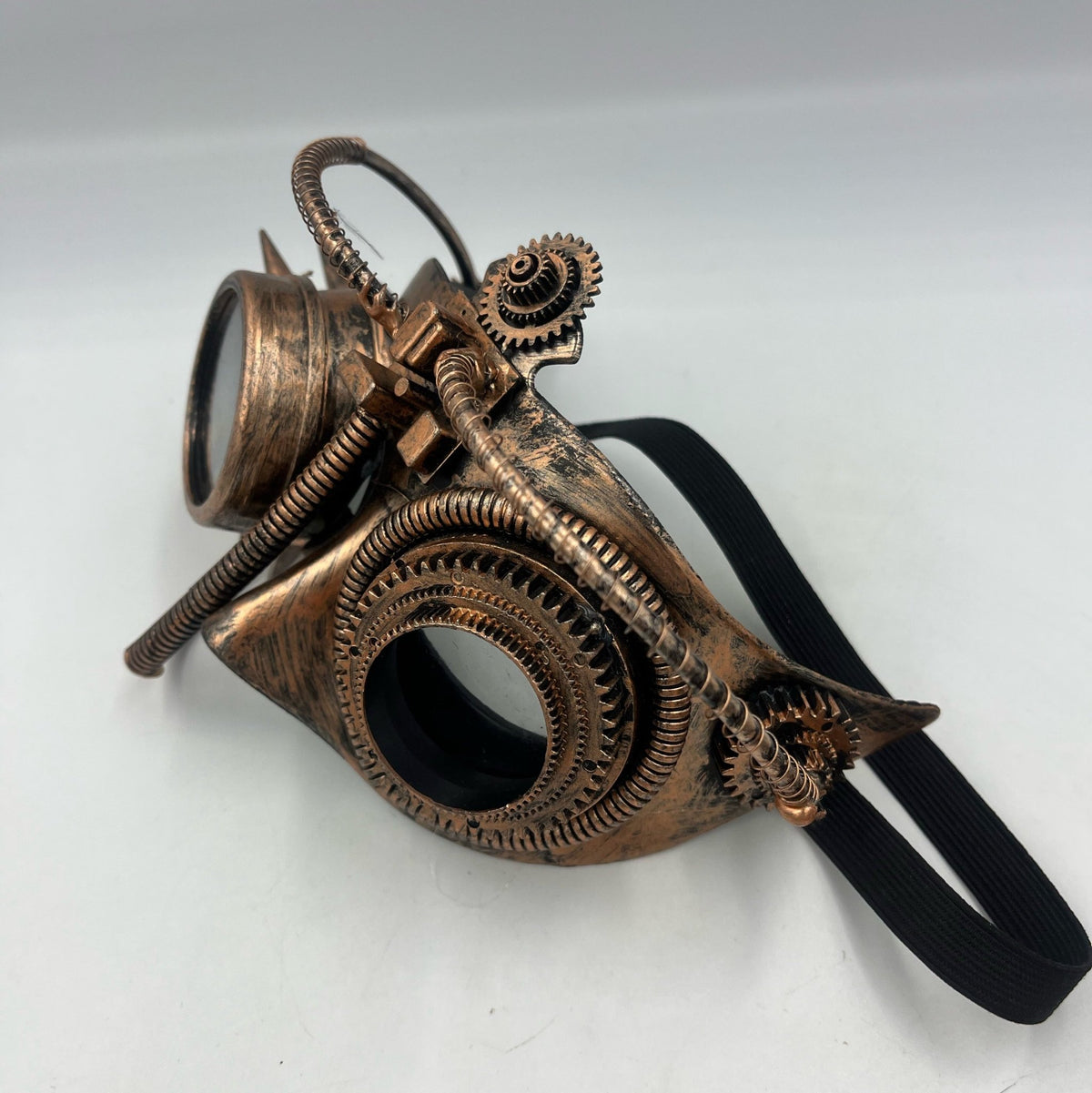 Side view of bronze-coloured steampunk goggles with gear-rimmed lenses, coiled tubing and a black strap, Steampunkgearsa.